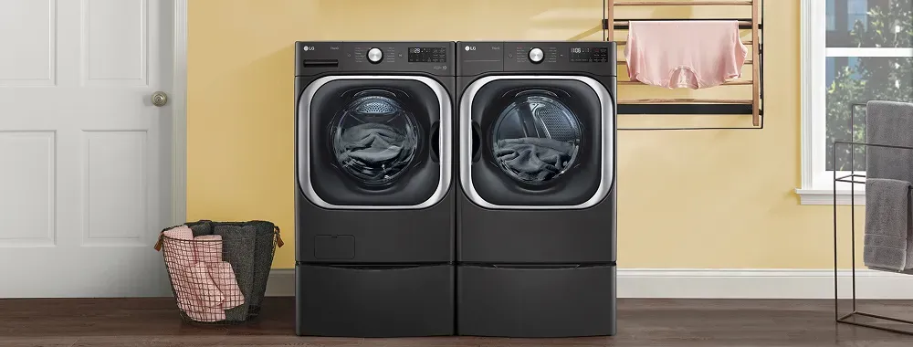 LG black front-load washing machine and gas dryer with pedestals in a modern laundry room